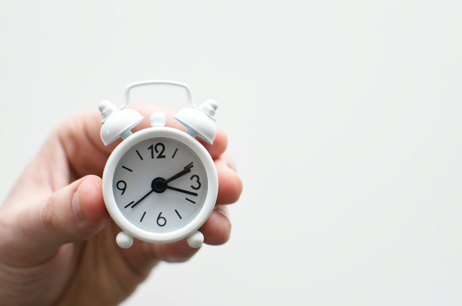 person holding white mini bell alarmclock